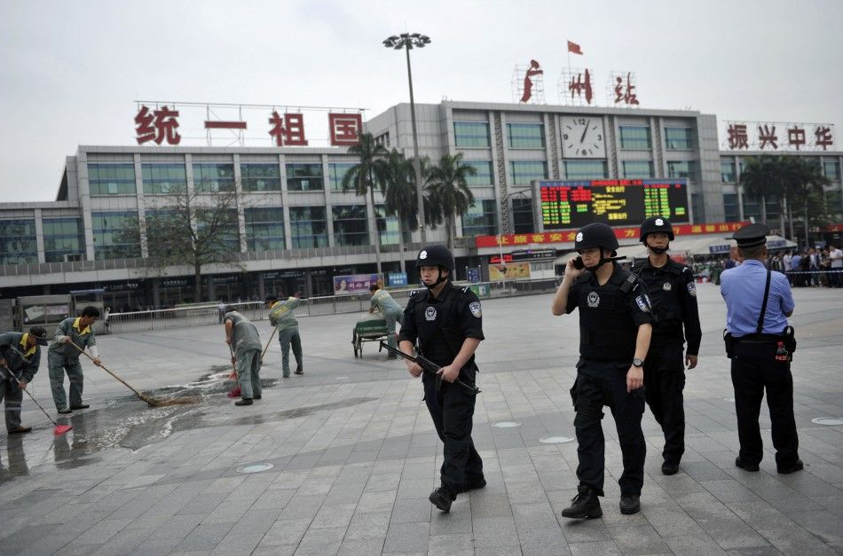 Armed policemen R patrol as workers clean the pavement after a knife attack at a railway station in Guangzhou, Guangdong province May 6, 2014. At least two and as many as four attackers wielding long knives wounded six people in an attack at a railway s