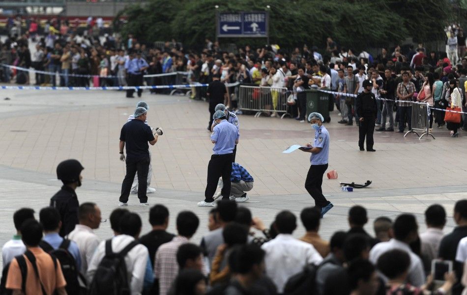 People look on as police officers investigate at the scene after a knife attack at a railway station in Guangzhou, Guangdong province May 6, 2014. Six people were wounded in a knife attack at a railway station in the southern Chinese city of Guangzhou on 