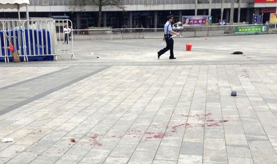 A policeman walks past blood stains on the ground after a knife attack at a railway station in Guangzhou, Guangdong province May 6, 2014. Six people were wounded in a knife attack at a railway station in the southern Chinese city of Guangzhou on Tuesday, 