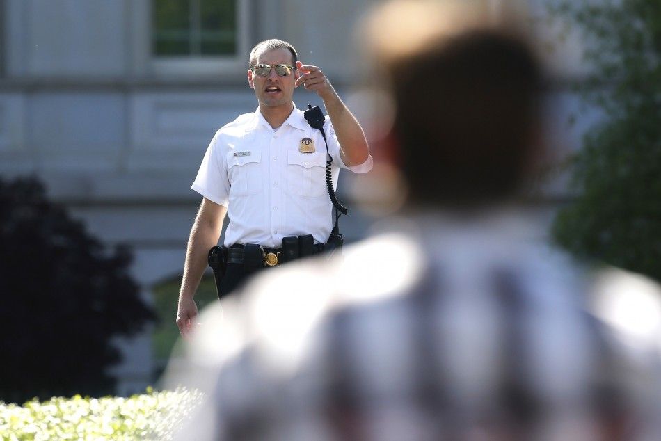 A member of the Uniformed Division of the Secret Service clears television journalists from their positions along the driveway at the White House after a motorist attempted to drive through a secure area near the White House gates in Washington May 6, 201