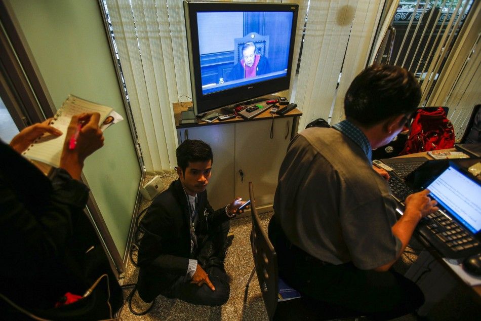 Reporters listen as the verdict is given at the Constitutional Court in Bangkok May 7, 2014. A Thai court found Prime Minister Yingluck Shinawatra guilty on Wednesday of violating the constitution and said she had to step down, although ministers not impl