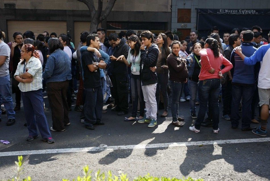People stand on a street after evacuating a building following an earthquake in Mexico City April 18, 2014. 