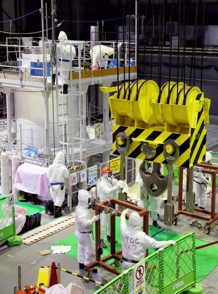 Workers wearing protective suits conduct decontamination operation to the equipments for removal spent fuel rods from the spent fuel pool inside the No.4 reactor building at the tunami-crippled Tokyo Electric Power Co's (TEPCO) Fukushima Daiichi nuclear p