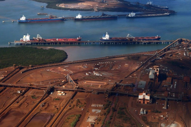 Ships waiting to be loaded are seen near piles of iron ore and bucket-wheel reclaimers at the Fortescue loading dock located at Port Hedland, in the Pilbara region of Western Australia in this December 3, 2013 file photograph. 