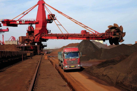 A truck drives past piles of iron ore at the dump site of a port in Rizhao, Shandong province in this October 3, 2013 file photo. 