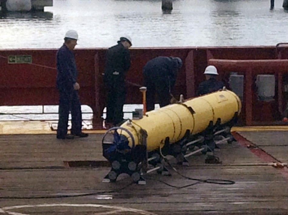 Workers on the ship Ocean Shield stand alongside the U.S. Navys Bluefin-21 autonomous underwater vehicle at Her Majestys Australian Ship HMAS Base Stirling, south of Perth, May 10, 2014. The Australian naval vessel carrying the underwater drone involv