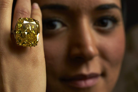 A model poses with a vivid yellow 100.09 carats diamond during an auction preview at Sotheby&#039;s in Geneva