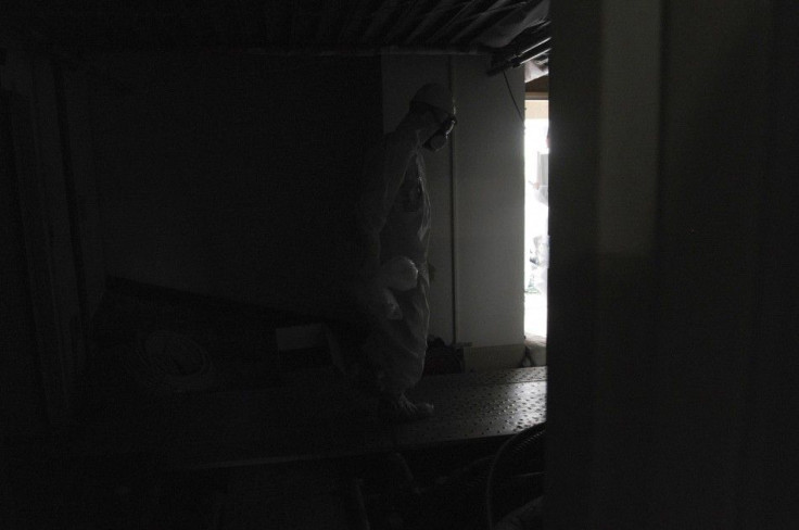 Wearing a protective suit and a mask, an employee of Japan's Tokyo Electric Power Co. (TEPCO) walks carefully along a dark aisle after U.S. Ambassador to Japan Caroline Kennedy visited the central control room for the unit one and unit two reactors at TEP