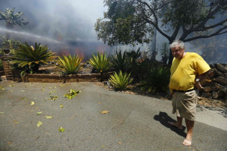 Greg Saska watches as his mother's home goes up in flames as fire fighters battle wildfires in Carlsbad, California  May 14,  2014.     REUTERS/Mike Blake