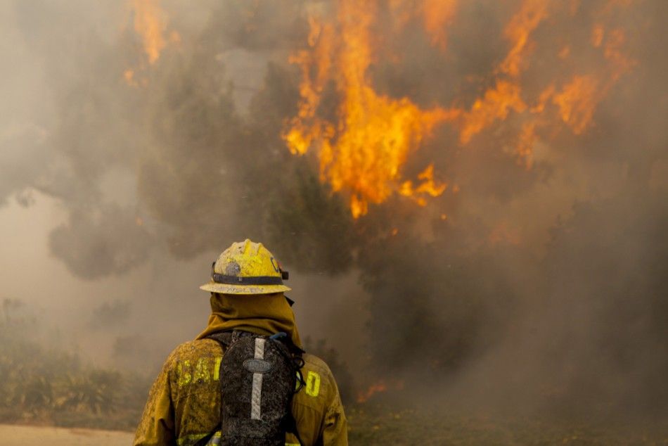 Firefighters battle the so-called Poinsettia Fire in Carlsbad, California May 14, 2014. At least two structures burned to the ground and some 15,000 homes and businesses were told to evacuate on Wednesday as the wind-lashed wildfire roared out of control 