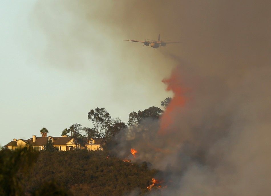A water bomber drops fire retardant to help save a home on a hillside after another wildfire near San Diego erupted near San Marcos, California May 14, 2014. More than 20 structures, including several homes, burned to the ground and thousands of people we