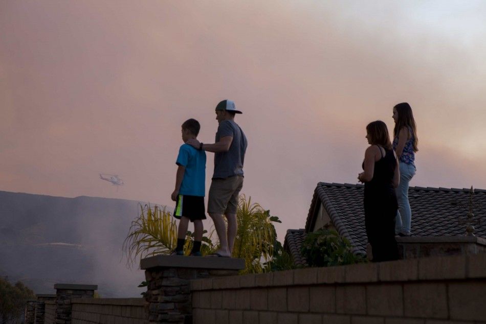Residents watch as firefighters battle a blaze in San Marcos, California May 14, 2014. California fire crews, helped by diminished overnight winds, made substantial headway by early Wednesday against a blaze that had prompted thousands of evacuations in a