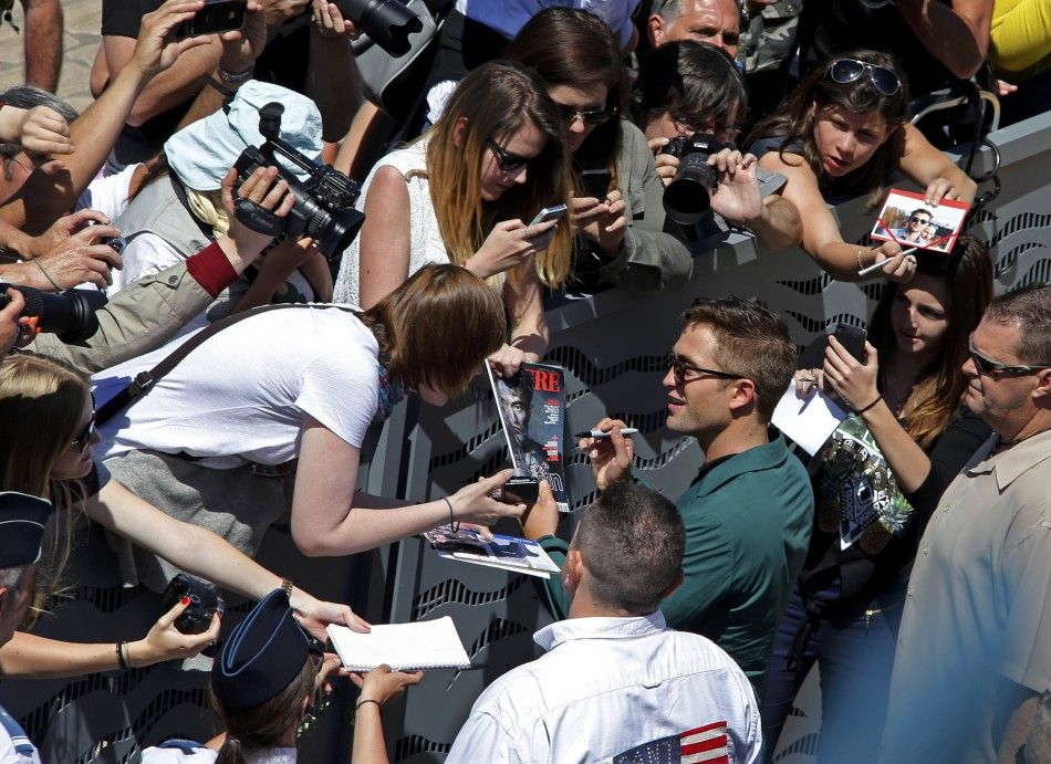 Cast member Robert Pattinson signs autographs as he arrives to attend a photocall for the film quotThe Roverquot out of competition at the 67th Cannes Film Festival in Cannes