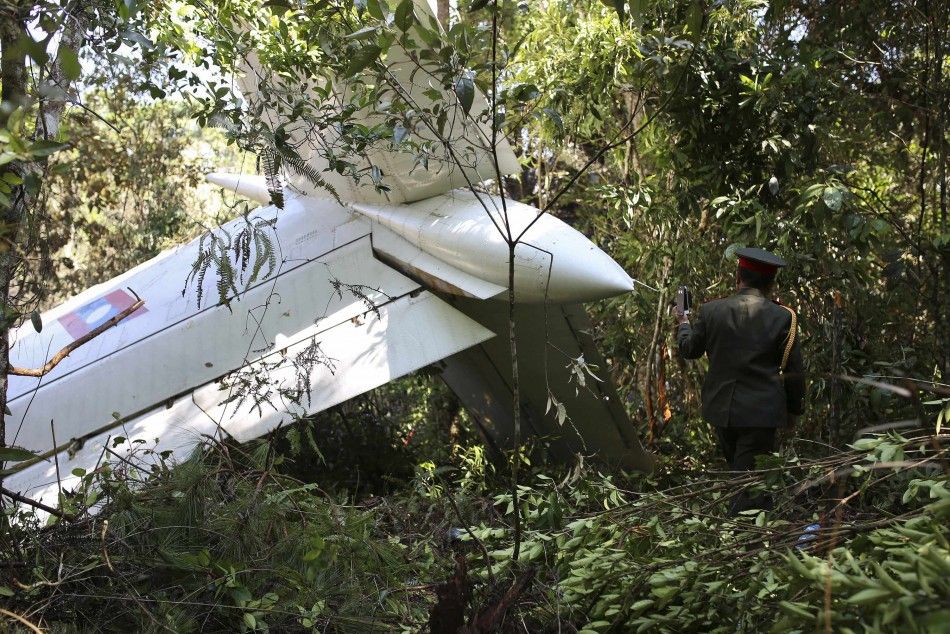 An officer takes pictures with his mobile phone at an air force plane crash site near Nadee village, in Xiang Khouang province in the north of the country May 17, 2014. The Laos air force plane with 14 people on board, including the defence minister, has 