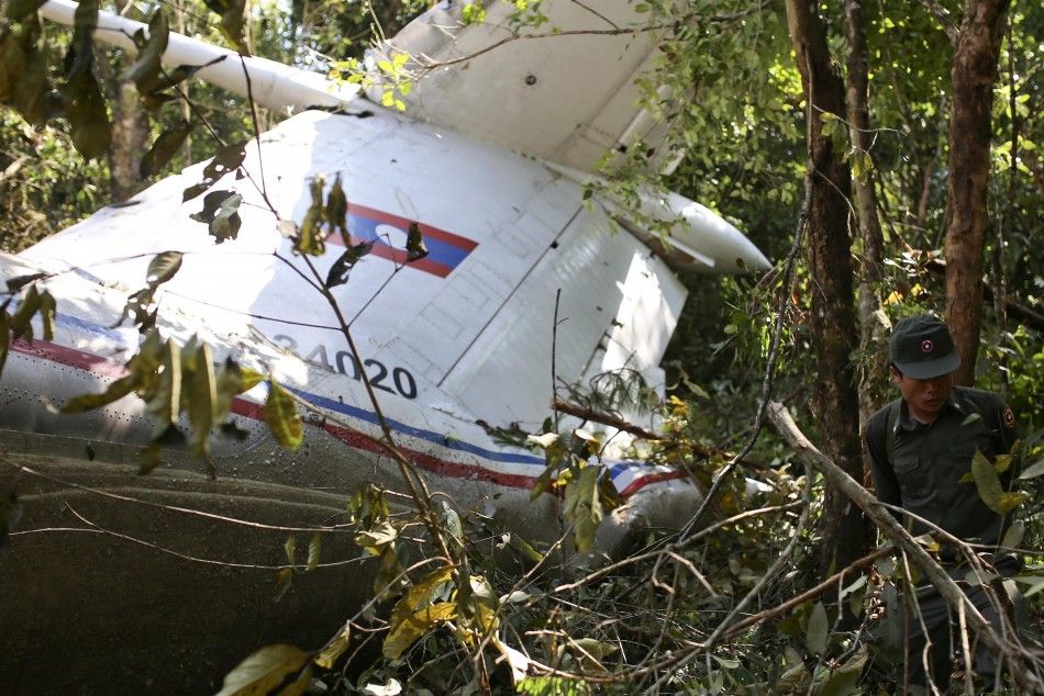 A rescue worker makes his way past the wreckage of an air force plane at its crash site near Nadee village, in Xiang Khouang province in the north of the country May 17, 2014. The Laos air force plane with 14 people on board, including the defense ministe