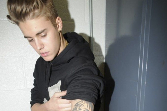 Canadian pop singer Justin Bieber shows his tattooed left arm, while in police custody in Miami Beach, Florida January 23, 2014 in this Miami Beach Police Department handout released to Reuters on March 4, 2014. Bieber was charged with driving under the i
