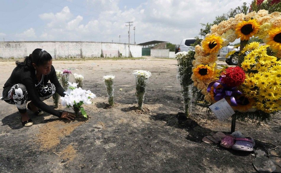 A relative places flowers at the site of a bus fire in Fundacion May 19, 2014. Thirty-one children and one adult were killed in Colombia on Sunday when fuel exploded on a broken-down bus returning from a church event, an emergency response coordinator sai