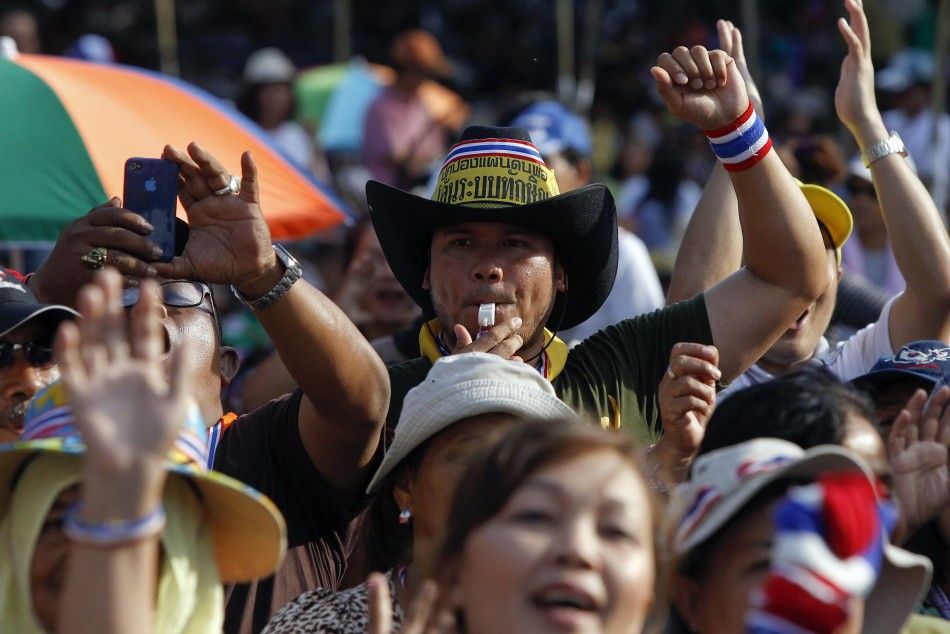 An anti-government protester blows a whistle as other cheer during a rally near the Government House in Bangkok May 20, 2014. 