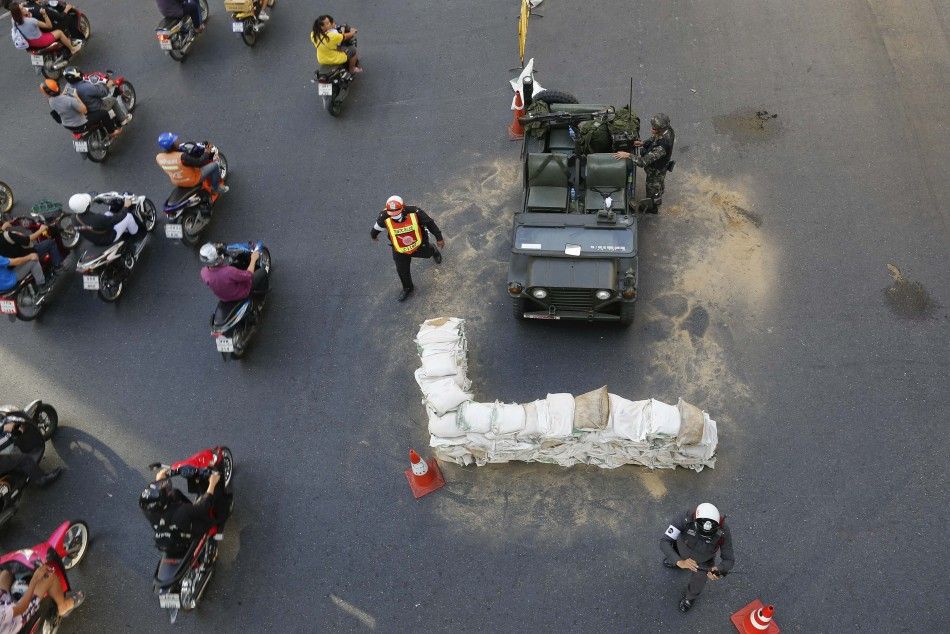 Commuters drive their motorcycles past Thai soldiers positioned in the middle of a main intersection in Bangkoks shopping district May 20, 2014. 