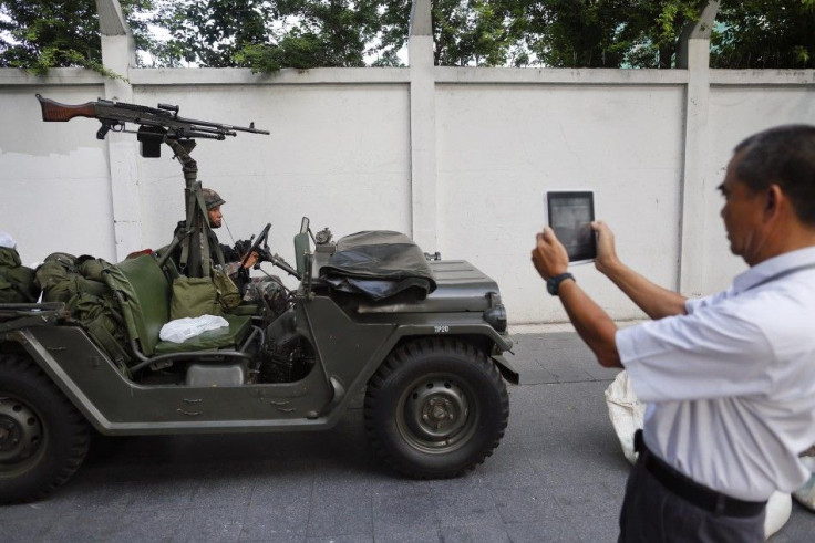 A man takes pictures of a soldier sitting in a military vehicle, with a machine gun mounted on it, after the Thai army took their positions in central Bangkok May 20, 2014. 