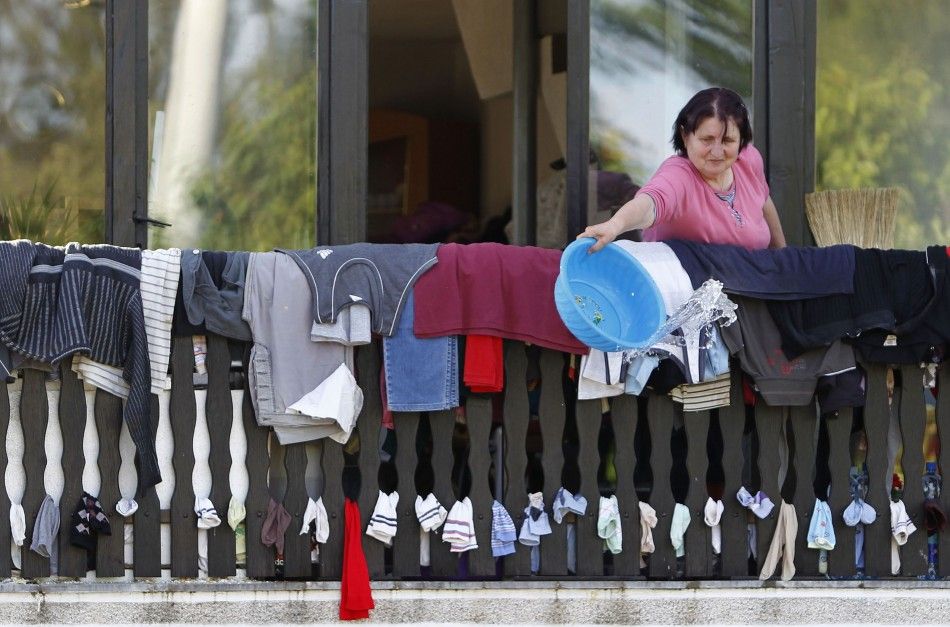 A woman throws away water as she dries clothes during heavy floods in Bosanski Samac May 19, 2014. Bosnia said on Monday that more than a quarter of its 4 million people had been affected by the worst floods to hit the Balkans in living memory, comparing 