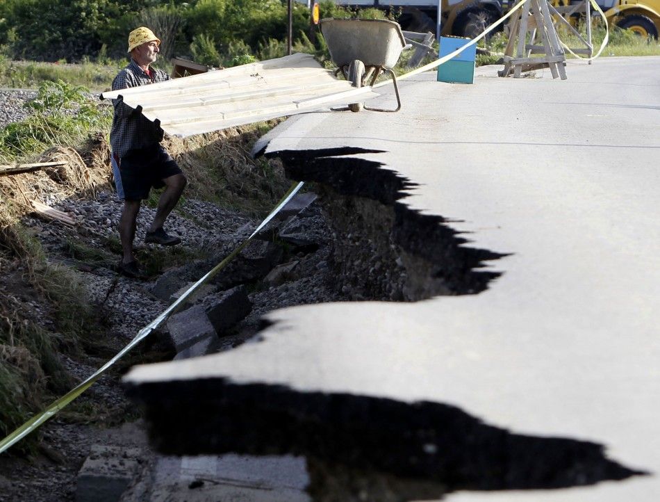 A man is seen next to a damaged road as he collects building materials after heavy floods in Bosanski Samac May 19, 2014. Bosnia said on Monday that more than a quarter of its 4 million people had been affected by the worst floods to hit the Balkans in li