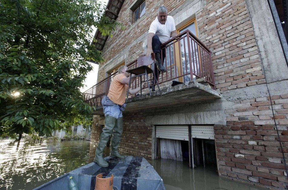 A man climbs on the balcony of his house during heavy floods in Bosanski Samac May 19, 2014. 