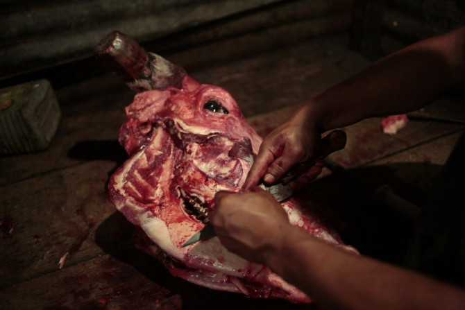 A man uses a knife to strip meat off a cow's skull in the &quot;Cholojeros&quot; zone next to the railway lines at Zona 18, in Guatemala City