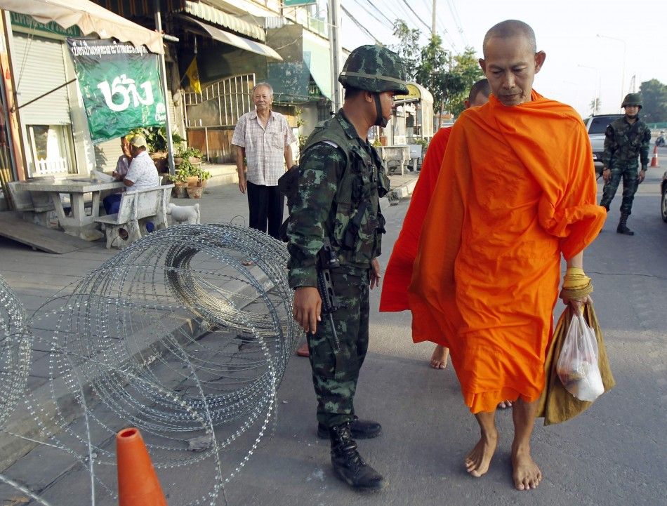 Barefoot Buddhist monks walk past soldiers at a checkpoint near a pro-government quotred shirtquot supporters encampment in Nakhon Pathom province on the outskirts of Bangkok May 22, 2014. Thailands rival political factions would not agree to stop s