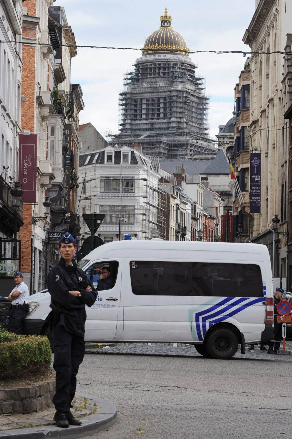 A policewoman and a police vehicle are seen at the site of a shooting in central Brussels May 24, 2014. Three people were killed in the shooting near the citys Jewish Museum on Saturday, the Belga news agency reported, quoting a fire brigade official.   