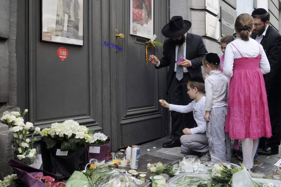 A family lights candles at the Jewish Museum, site of a shooting in central Brussels May 25, 2014. Belgian police were hunting on Sunday for an assailant who shot dead three people at the Jewish Museum in Brussels, and French authorities tightened securit