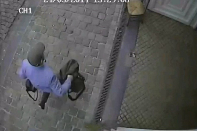 A man holding a black bag is seen leaving the Jewish Museum in Brussels, in this still image taken from the video of a security camera, which was distributed to the media by the Belgian police on May 25, 2014.  Belgian police were hunting on Sunday for an