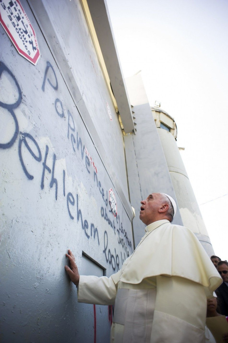 Pope Francis touches the wall that divides Israel from the West Bank, on his way to celebrate a mass in Manger Square next to the Church of the Nativity in the West Bank city of Bethlehem May 25, 2014. 