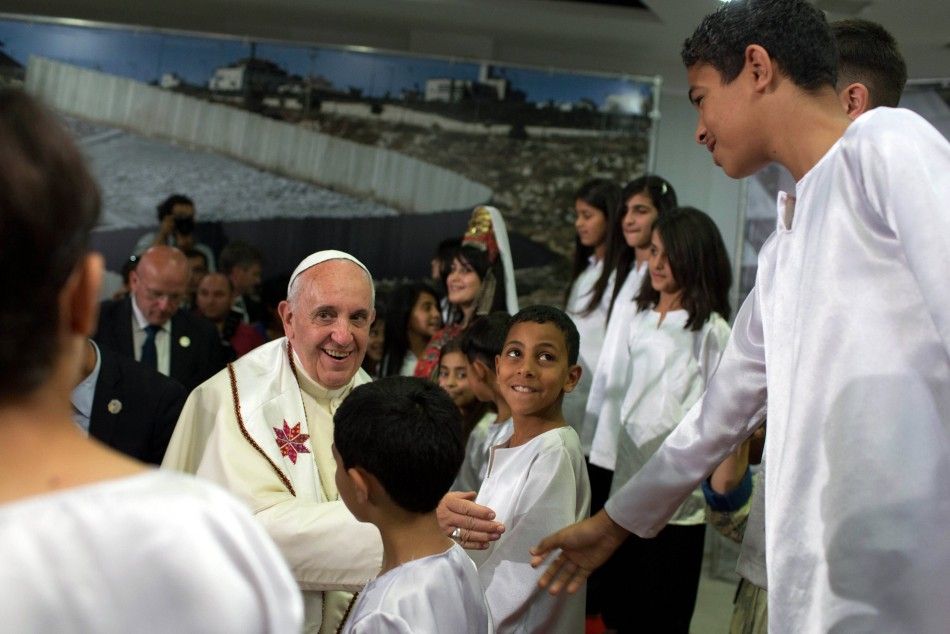 Pope Francis shakes hands with a boy, who is from a nearby Palestinian refugee camp, during a visit to the Dheisheh refugee camp on the outskirts of the West Bank city of Bethlehem May 25, 2014. Pope Francis made a surprise stop at the hulking wall Palest