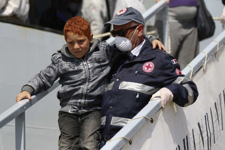 A child is helped by a Red Cross member as he is disembarked from a navy ship in the Sicilian harbour of Augusta May 22, 2014. More than 100 children were among the 488 migrants rescued by the Italian Navy off the Sicilian coast on May 21, 2014 as the inf