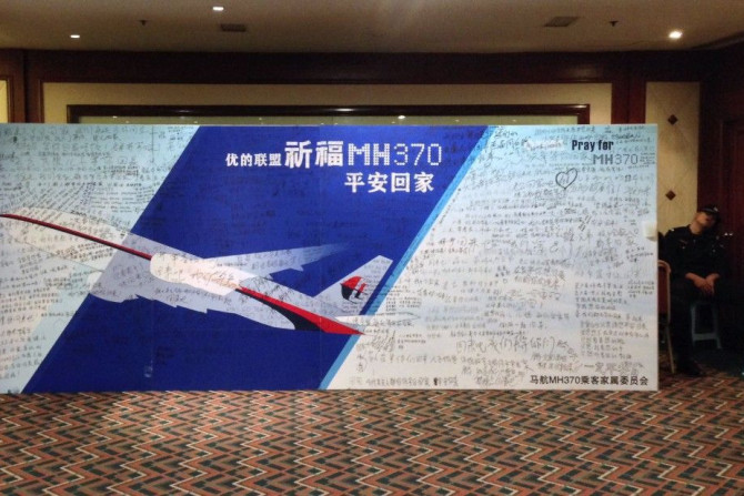 A policeman takes a nap beside a board written with messages for passengers onboard the missing Flight MH370 in Beijing
