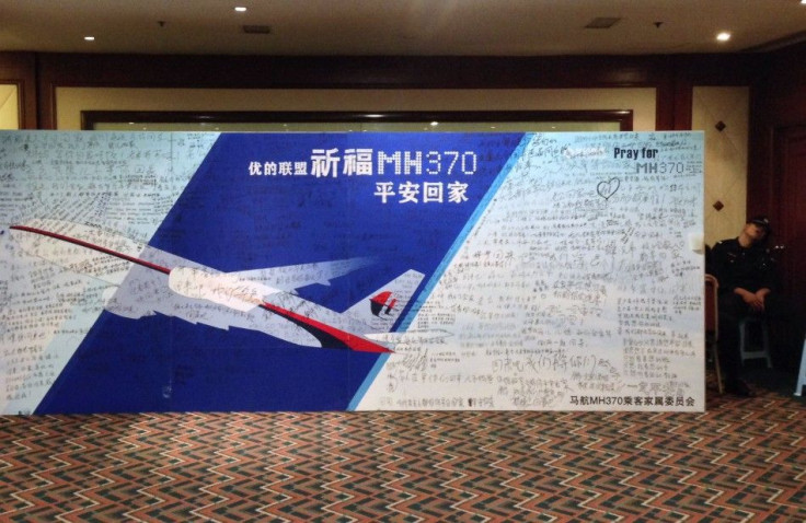 A policeman takes a nap beside a board written with messages for passengers onboard the missing Flight MH370 in Beijing