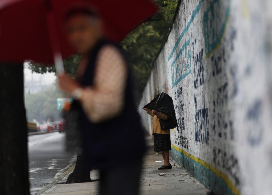 Women cover themselves as it continues to drizzle after torrential rains hit several neighborhoods in Mexico City May 26, 2014. Hurricane Amanda, the first named storm of the Pacific season, moved on Monday losing strength against Mexicos Pacific coast a