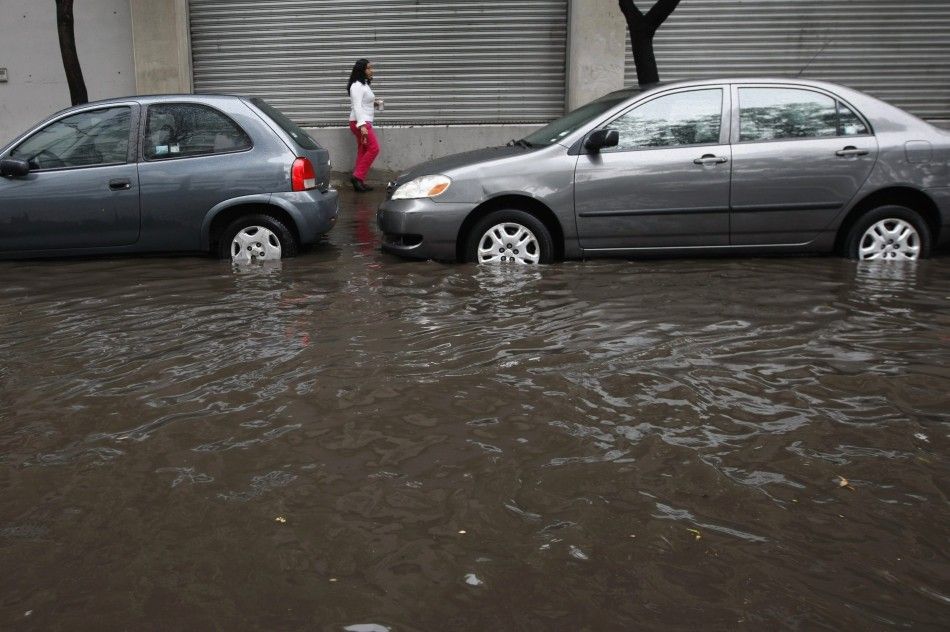 A woman walks on a sidewalk next to a flooded street after torrential rains hit several neighborhoods in Mexico City May 26, 2014. Hurricane Amanda, the first named storm of the Pacific season, moved on Monday losing strength against Mexicos Pacific coas