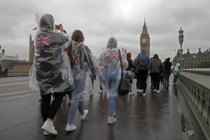 Tourists wear rain ponchos on Westminster Bridge near the Houses of Parliament in London May 27, 2014. REUTERS/Luke MacGregor