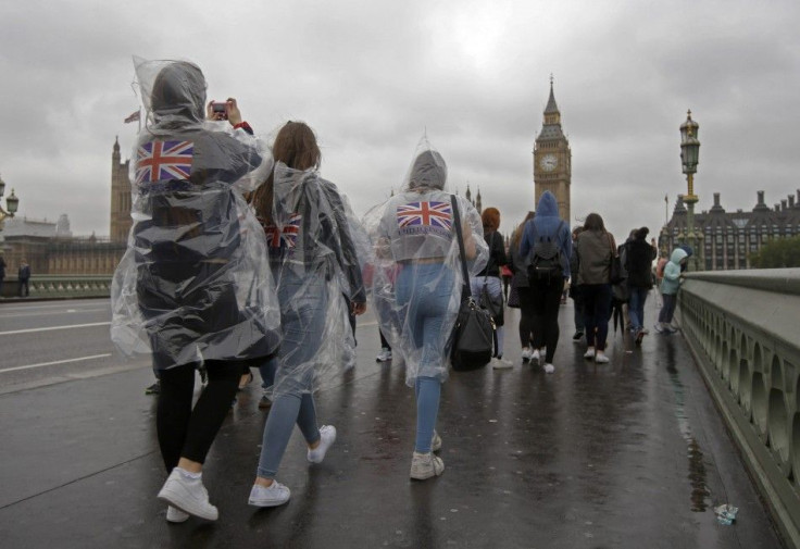 Tourists wear rain ponchos on Westminster Bridge near the Houses of Parliament in London May 27, 2014. REUTERS/Luke MacGregor