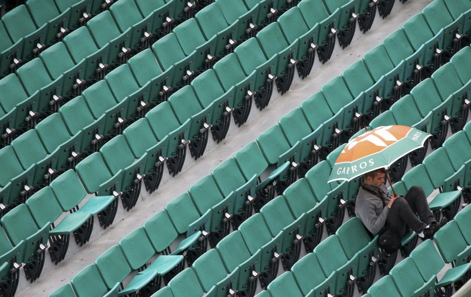 A spectator protects himself from rain during a mens singles match between Novak Djokovic of Serbia and Joao Sousa of Portugal at the French Open tennis tournament at the Roland Garros stadium in Paris May 26, 2014. REUTERSGonzalo Fuentes