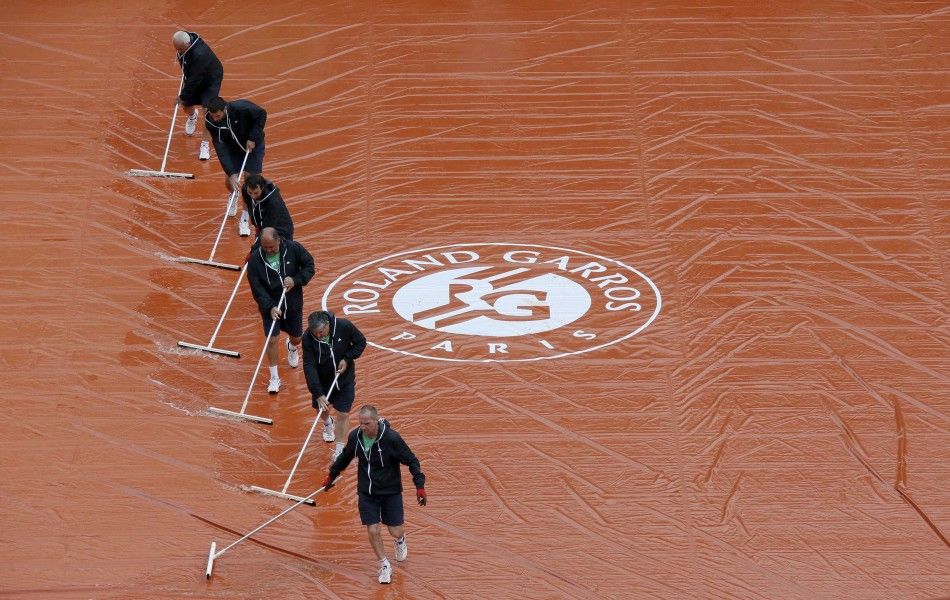 Workers sweep water off a tarp as rain interrupts a mens singles match between Novak Djokovic of Serbia and Joao Sousa of Portugal at the French Open tennis tournament at the Roland Garros stadium in Paris May 26, 2014. REUTERSGonzalo Fuentes