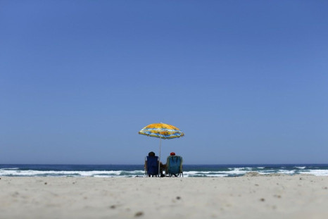 A Couple Sits Under an Umbrella for Shade from the Sun at the Beach in La Jolla, California