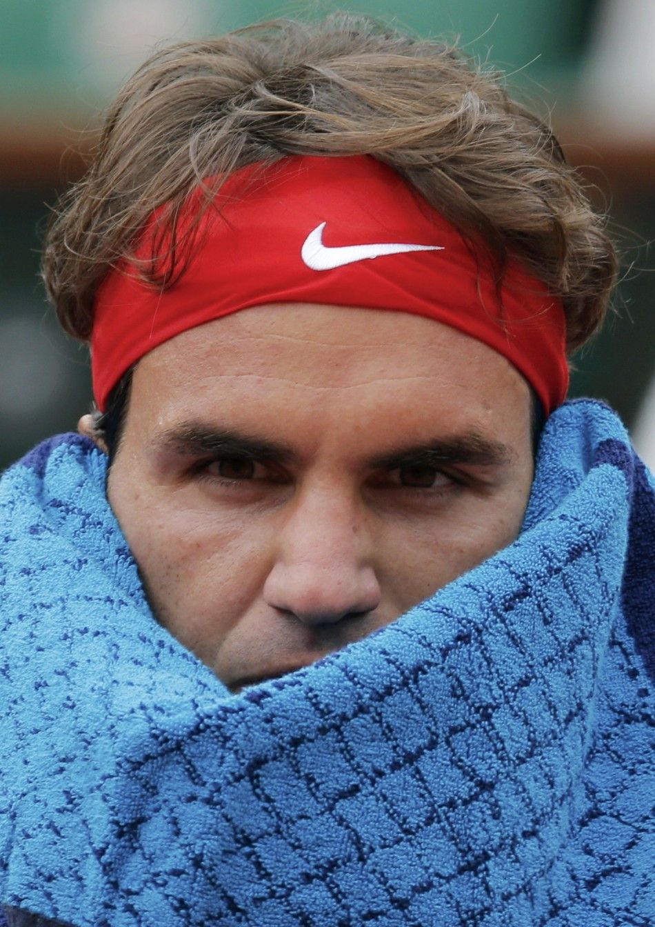 Roger Federer of Switzerland wipes his head with a towel during his mens singles match against Ernests Gulbis of Latvia at the French Open tennis tournament at the Roland Garros stadium in Paris June 1, 2014.