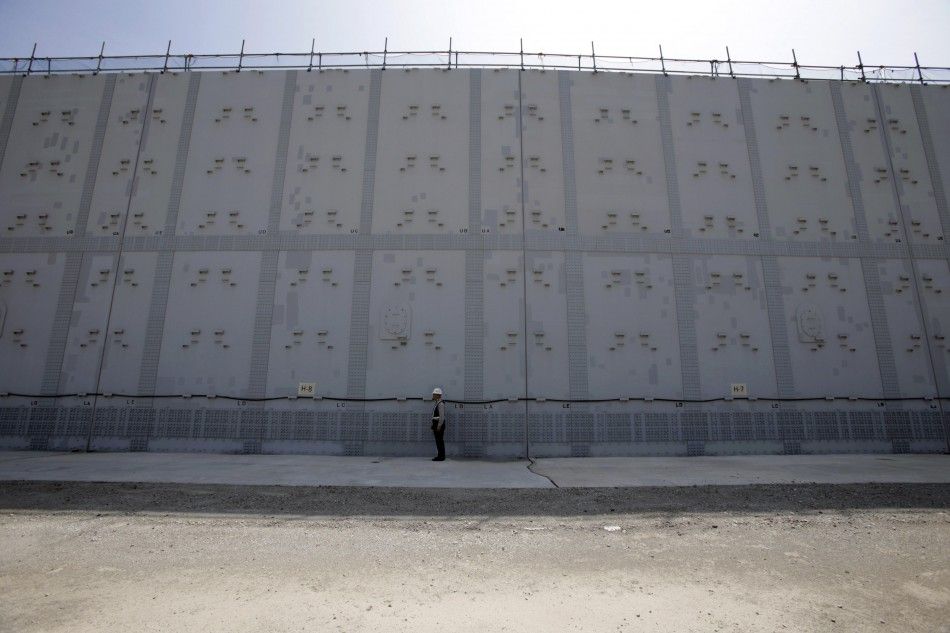 A worker stands in front of an 18-m 59-ft high and 1.6-km 1-mile long tsunami defence wall at Chubu Electric Power Co.s Hamaoka Nuclear Power Station in Omaezaki, Shizuoka Prefecture, in this file picture taken May 17, 2013. In the three years since 