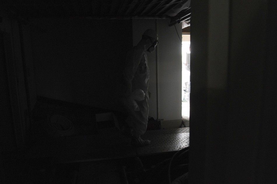 Wearing a protective suit and a mask, an employee of Japans Tokyo Electric Power Co. TEPCO walks carefully along a dark aisle after U.S. Ambassador to Japan Caroline Kennedy visited the central control room for the unit one and unit two reactors at TEP