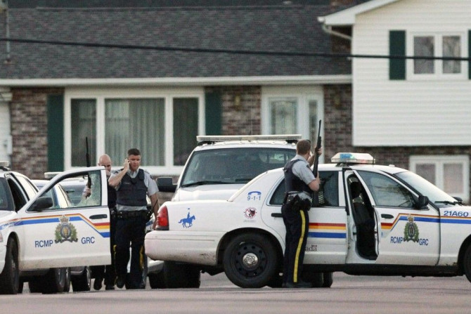 Codiac RCMP officers take cover behind their vehicle in Moncton