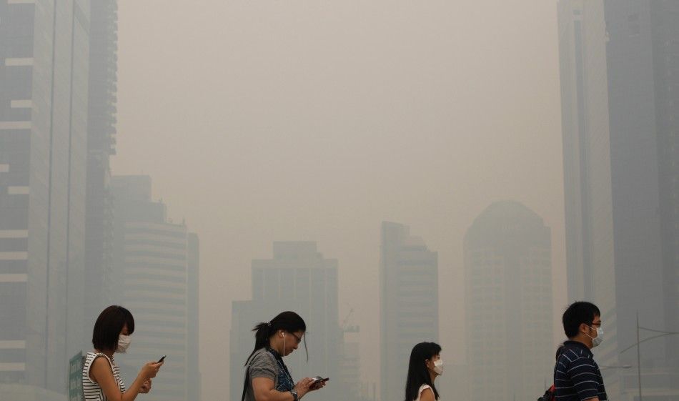 Office workers wearing masks make their way to work in Singapores central business district in this June 21, 2013 file photo. Singapore is approaching its yearly quothazequot season, when smoke from forest clearing in Indonesia chokes the air, with 2