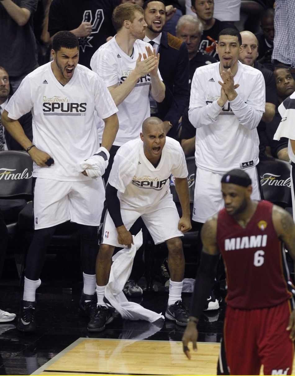 San Antonio Spurs players cheer a basket as Miami Heats LeBron James R walks across the court during the second quarter in Game 1 of their NBA Finals basketball series in San Antonio, Texas June 5, 2014.